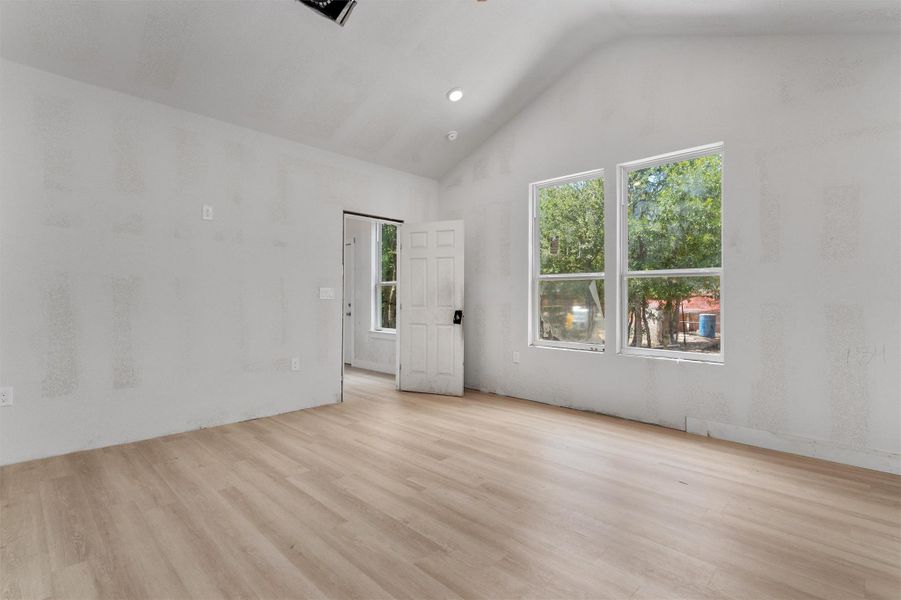 Spare room featuring light wood-style flooring, high vaulted ceiling, and recessed lighting Spare room featuring light wood-style flooring, high vaulted ceiling, and recessed lighting