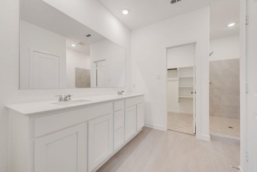 Bathroom featuring a shower stall, double vanity, light wood finished floors, recessed lighting, and a walk in closet Bathroom featuring a shower stall, double vanity, light wood finished floors, recessed lighting, and a walk in closet