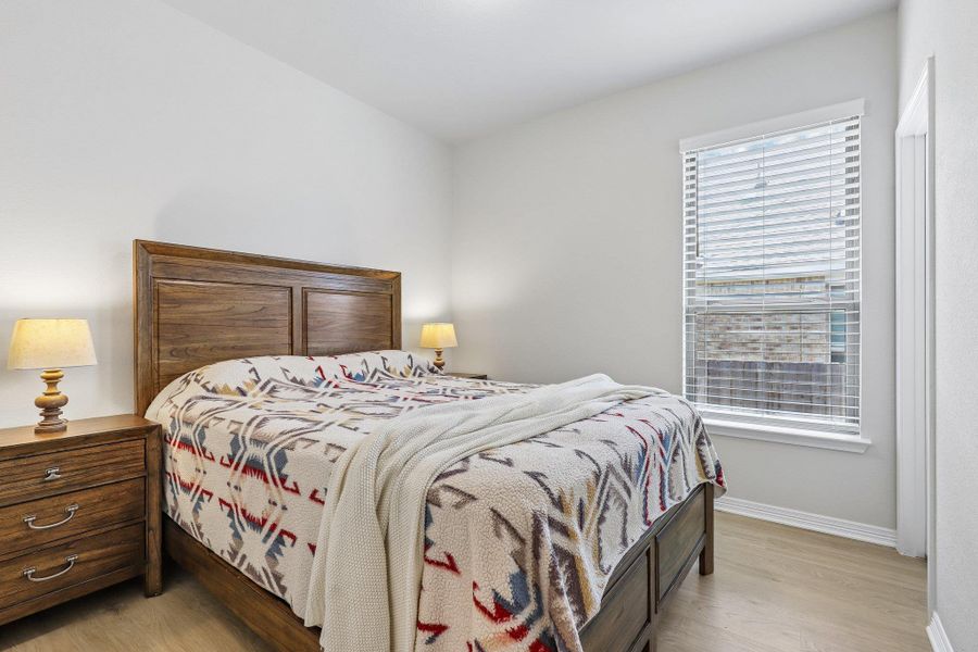 A well-lit room offers wood flooring and a large window, providing a serene retreat.