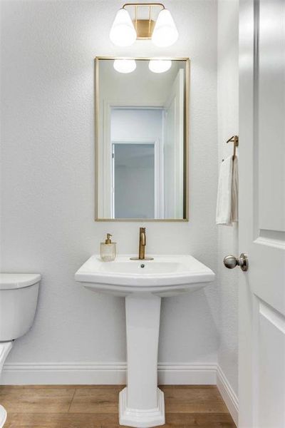 Half bath featuring toilet and wood finished floors