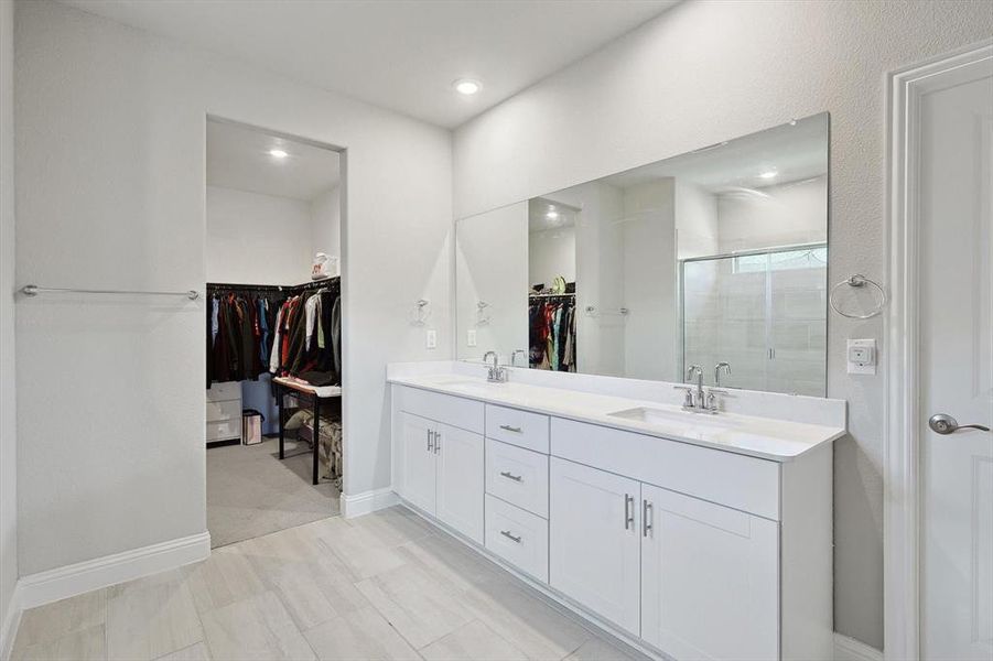 Bathroom featuring tile flooring, walk in shower, dual sinks, and large vanity