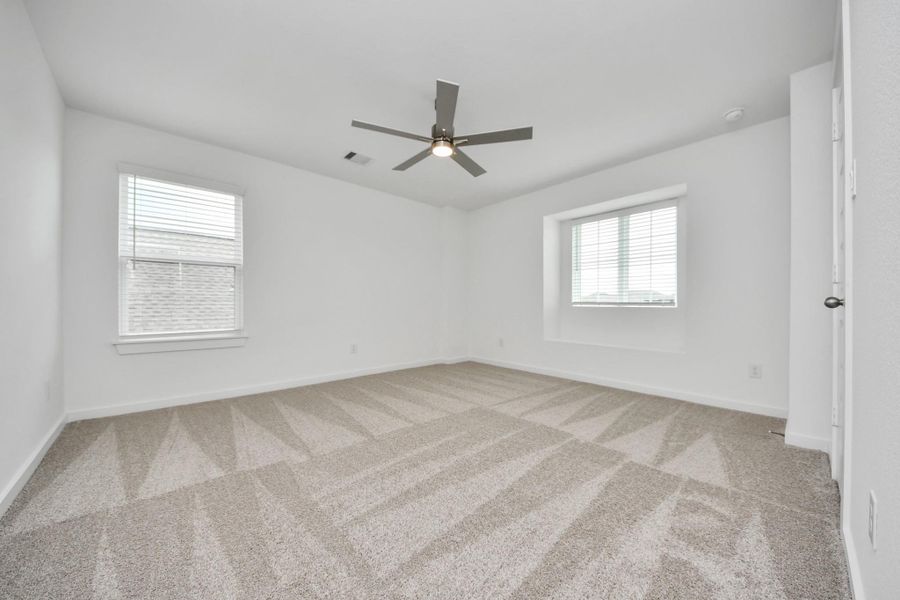 Secondary bedroom features plush carpeting, large windows that let in plenty of natural light, bright paint, and spacious closets. Sample photo of completed home with similar floor plan. Actual colors and selections may vary.