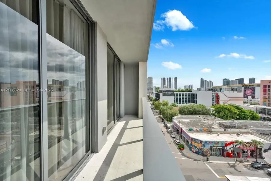 Private covered balcony featuring neutral tile flooring, floor-to-ceiling glass doors, and a sleek metal railing