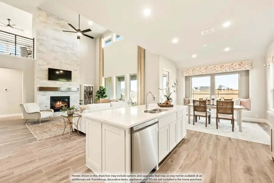 Open-concept kitchen with white island, stone fireplace, high ceilings, and dining area on wood-look floors