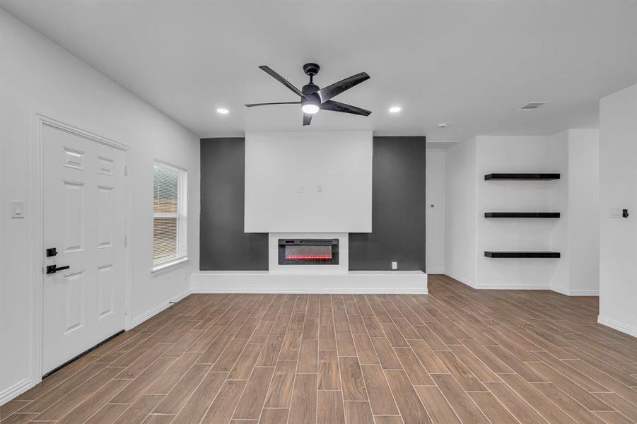 Unfurnished living room featuring heating unit, light hardwood / wood-style floors, and ceiling fan