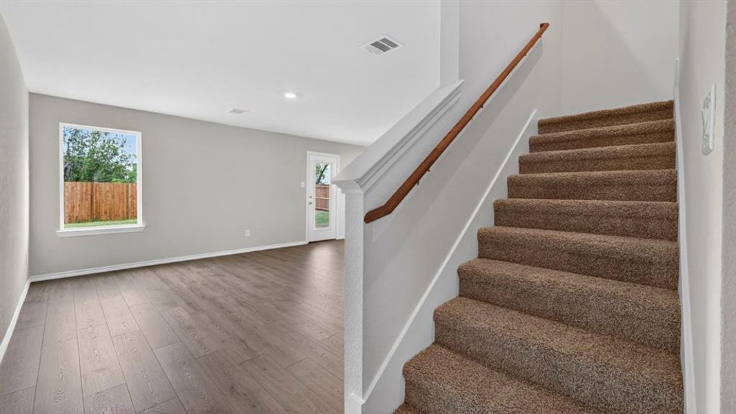 Carpeted staircase with a wood handrail, recessed lighting, wood-finish flooring, a rear window, and a back door Carpeted staircase with a wood handrail, recessed lighting, wood-finish flooring, a rear window, and a back door