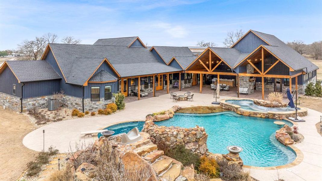 View of pool with a patio area, a pool with connected hot tub, and outdoor dining space