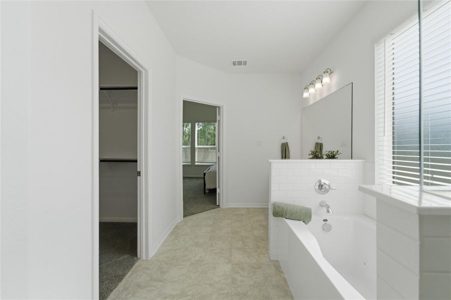 Indulge in a tranquil bathing experience in this well-lit primary bathroom featuring a deep soaking tub. Indulge in a tranquil bathing experience in this well-lit primary bathroom featuring a deep soaking tub.