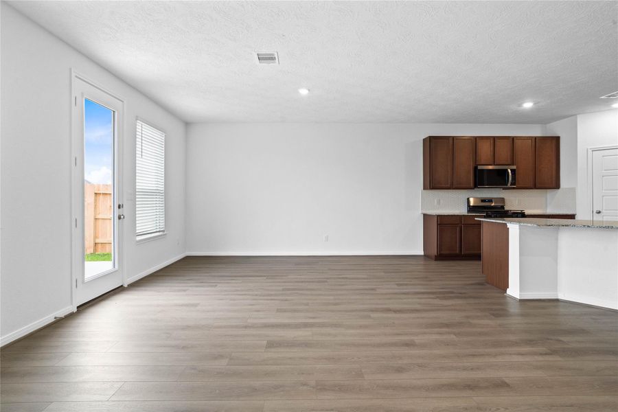Enjoy your morning coffee in this sun-drenched dining area, designed for family gatherings. The space features elegant vinyl plank flooring, recessed lighting, and a large window with privacy blinds. Seamlessly transition to outdoor living via the perfectly placed back patio door.