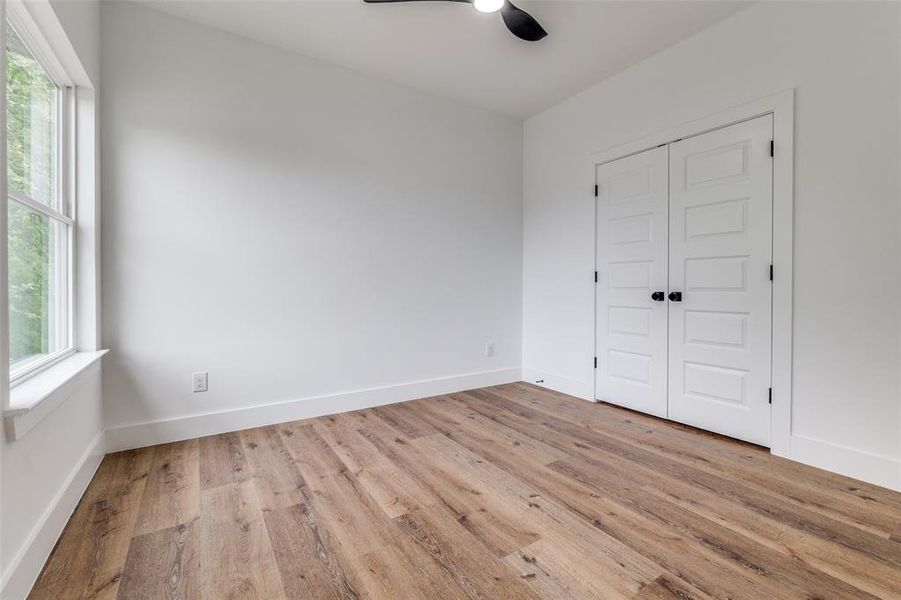 Second bedroom featuring a closet, multiple windows, and wood finished floors