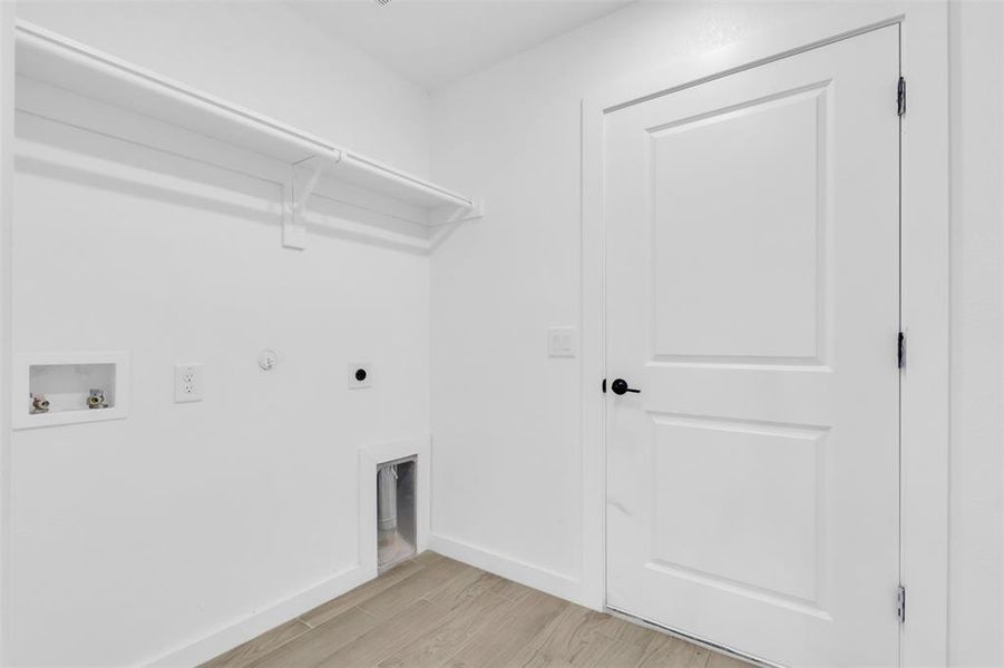 Washroom with hookup for a washing machine, electric dryer hookup, light wood-type flooring, and hookup for a gas dryer