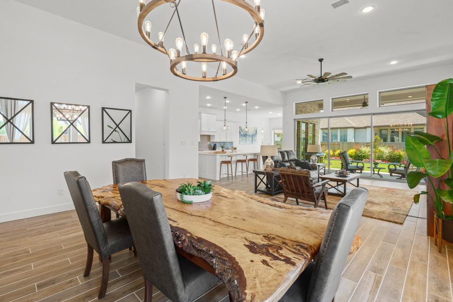 This photo showcases a spacious open-concept living area with high ceilings, and abundant natural light. The modern kitchen features sleek fixtures, and the living room opens to a beautifully landscaped backyard through large sliding doors. Perfect for entertaining and relaxation.
