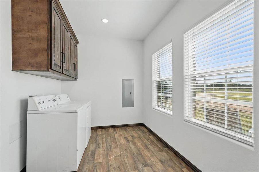 Laundry area featuring cabinet space, dark wood-type flooring, electric panel, independent washer and dryer, and recessed lighting Laundry area featuring cabinet space, dark wood-type flooring, electric panel, independent washer and dryer, and recessed lighting