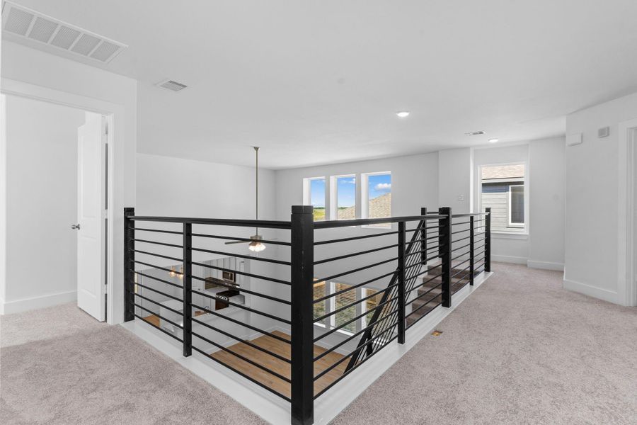 This upper-level hallway and dramatic catwalk overlook the main living space, offering both visual interest and easy access to upstairs bedrooms and the game room. Sleek cable iron railing adds a modern architectural touch. This upper-level hallway and dramatic catwalk overlook the main living space, offering both visual interest and easy access to upstairs bedrooms and the game room. Sleek cable iron railing adds a modern architectural touch.