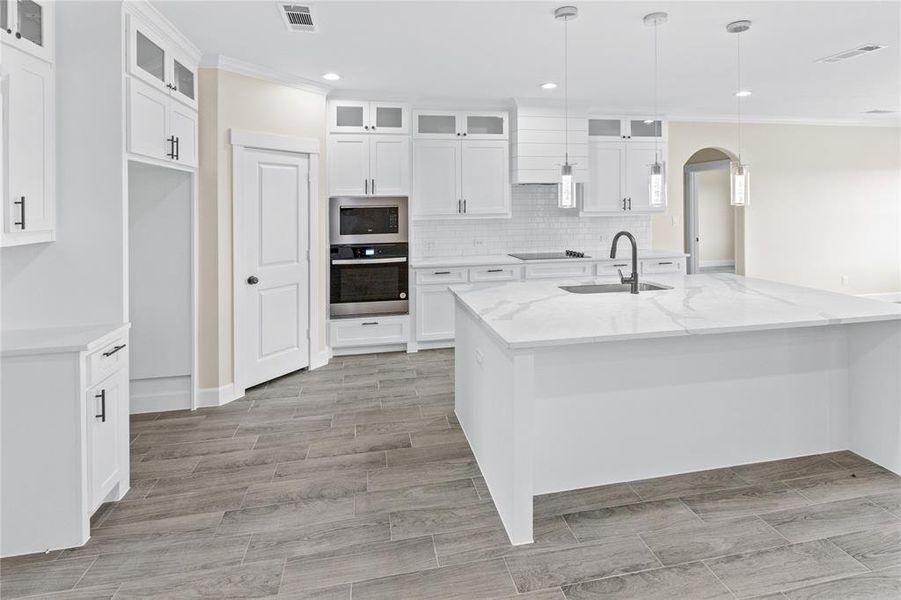 Kitchen featuring white cabinets, stainless steel appliances, decorative backsplash, and crown molding