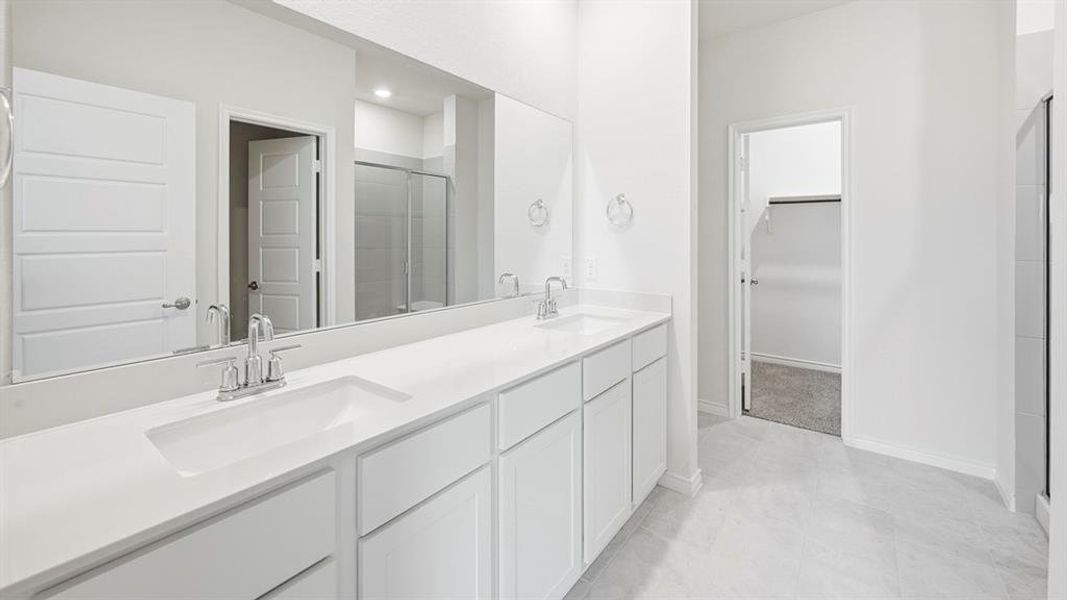 Bathroom featuring double vanity, a shower stall, and a walk in closet