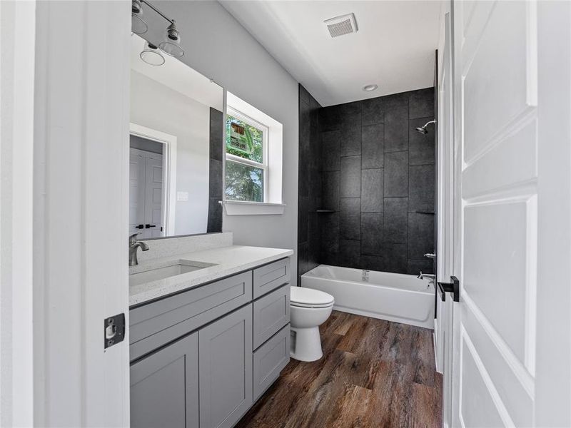 Full bathroom with toilet, wood finished floors, vanity, and shower / bathtub combination