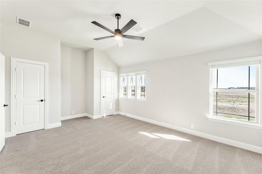 Empty bedroom with vaulted ceiling, ceiling fan, carpet flooring, and two windows with open views Empty bedroom with vaulted ceiling, ceiling fan, carpet flooring, and two windows with open views