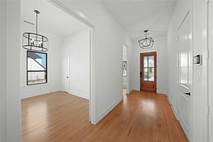 Foyer entrance featuring a chandelier and light wood-type flooring Foyer entrance featuring a chandelier and light wood-type flooring
