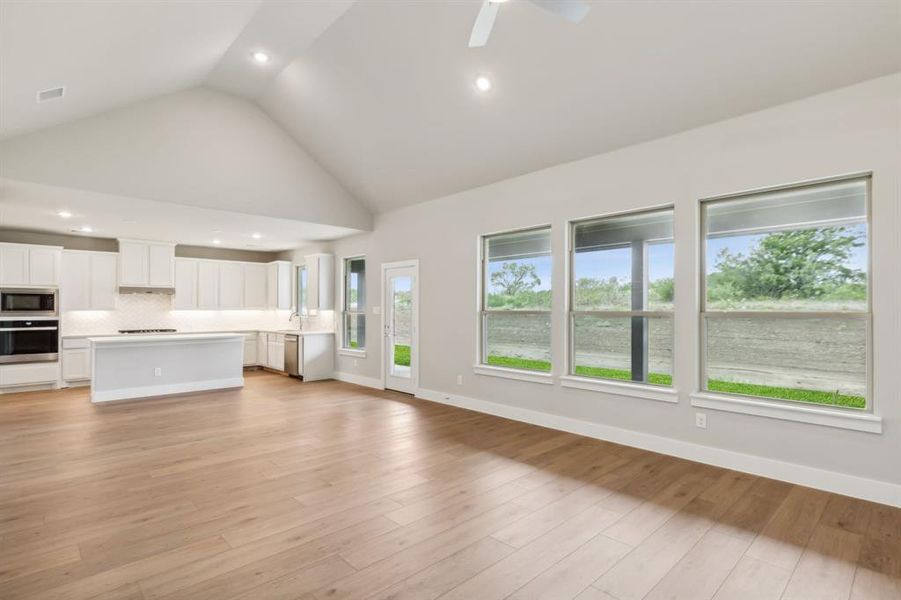 Unfurnished living room with high vaulted ceiling, light hardwood / wood-style flooring, and ceiling fan