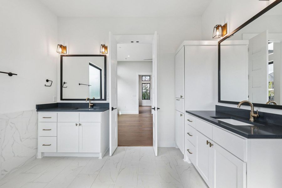 Full bath with two vanities and light marble finish floors