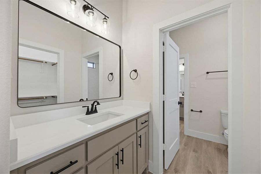Bathroom vanity featuring a rectangular undermount sink, light-toned countertop, and matte black faucet