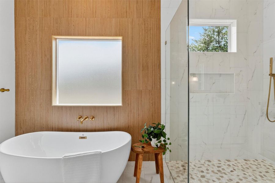 Full bath featuring a freestanding tub and a marble finish shower