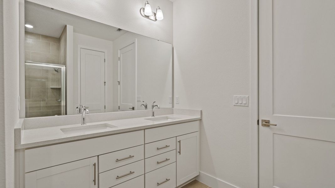 The Primary Suite en suite bath featuring dual bath sinks of the Buttonwood by DRB Homes at Trailside in Mount Dora, FL.
