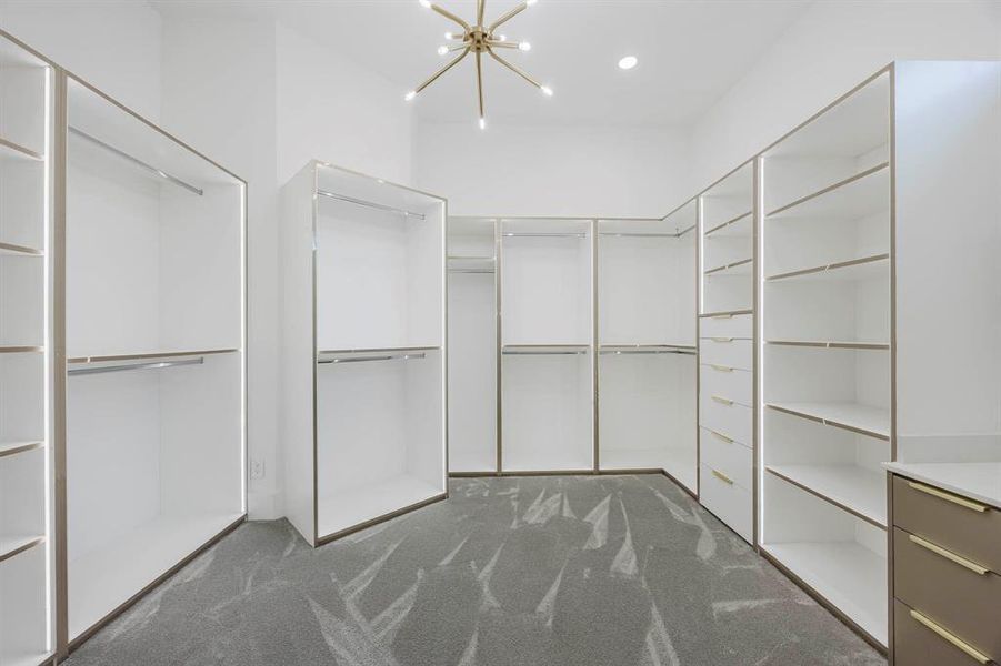 Spacious closet with a chandelier and dark colored carpet Spacious closet with a chandelier and dark colored carpet
