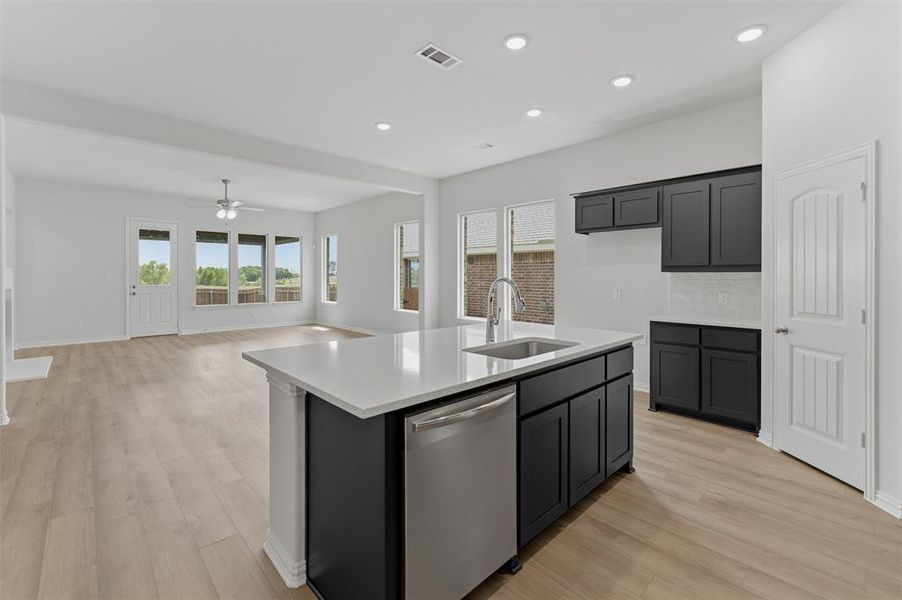 Kitchen island with white countertop, undermount sink, and stainless steel dishwasher Kitchen island with white countertop, undermount sink, and stainless steel dishwasher