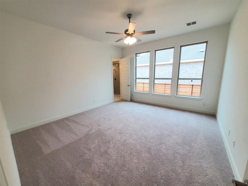 Empty room with baseboards, visible vents, ceiling fan, and carpet Empty room with baseboards, visible vents, ceiling fan, and carpet