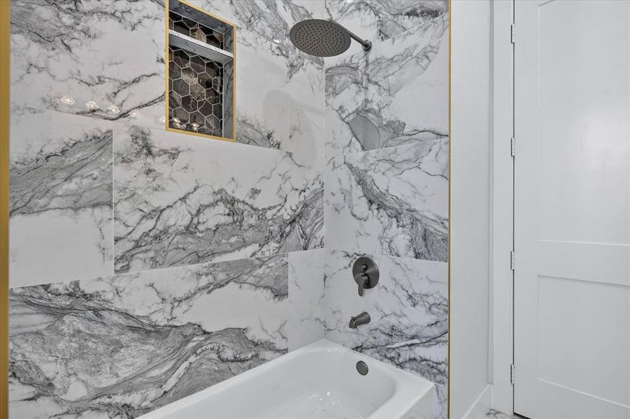 White tiled bath surround with gray veining and gold-finish trim White tiled bath surround with gray veining and gold-finish trim