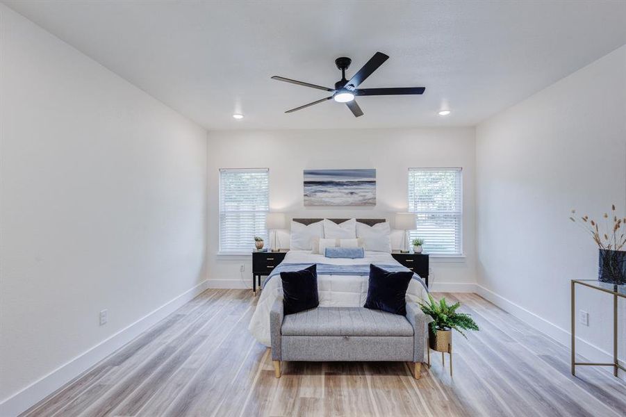 Bedroom with multiple windows, ceiling fan, and light hardwood / wood-style flooring