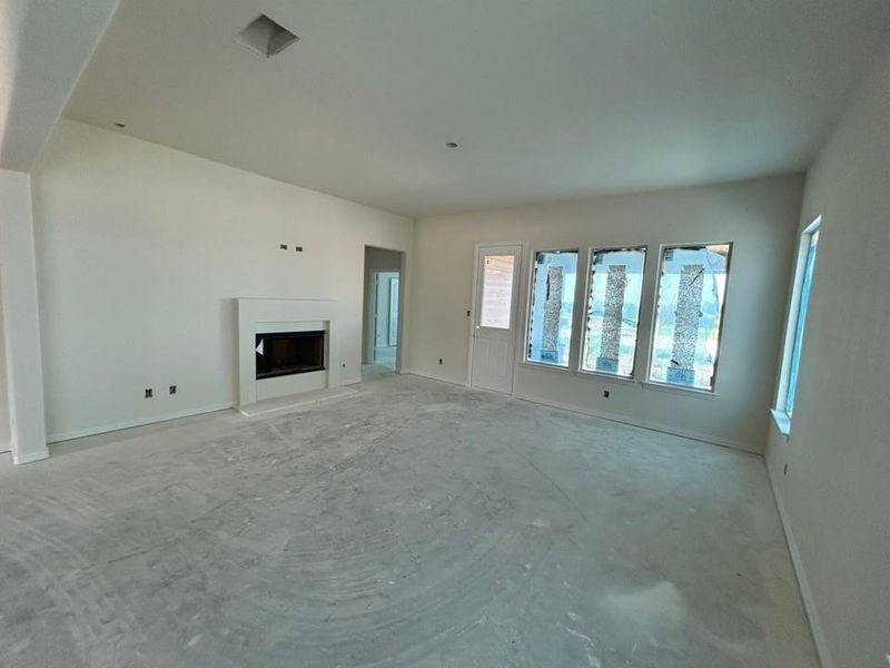 Unfurnished living room featuring a fireplace with raised hearth and baseboards