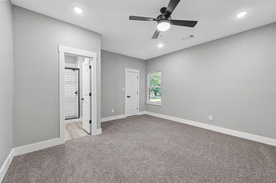 Unfurnished bedroom with ceiling fan, light colored carpet, and connected bathroom