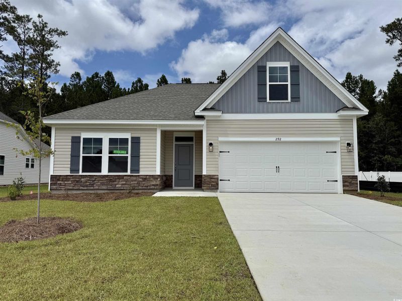 View of front of home with stone siding, board and batten siding, and concrete driveway