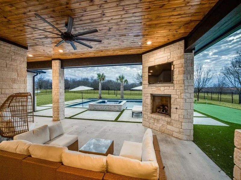 Fenced backyard featuring a patio area, a ceiling fan, a pool with connected hot tub, and an outdoor living space with a fireplace