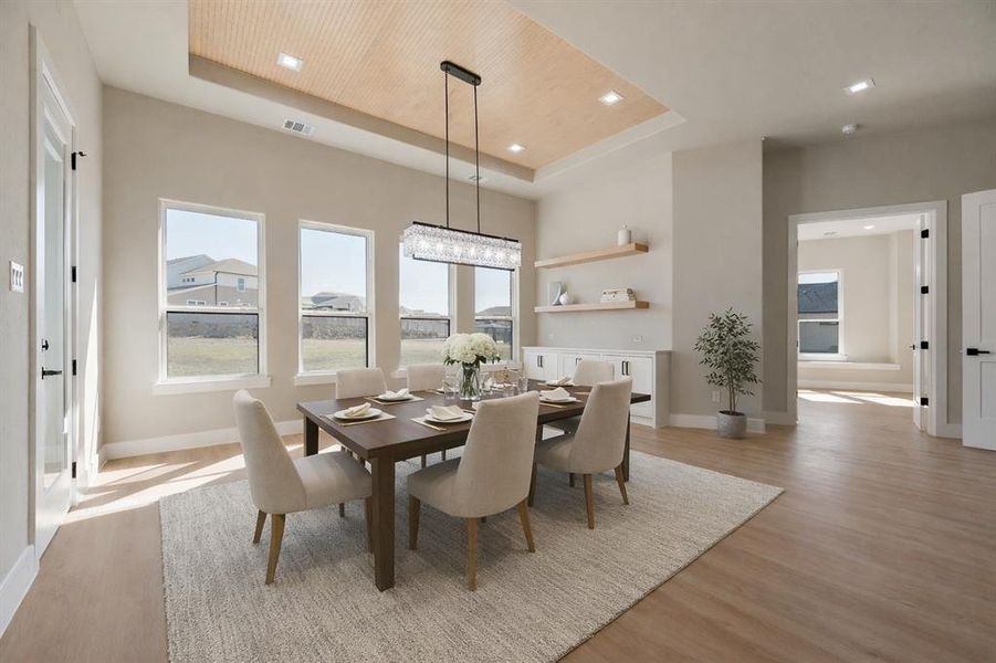 Dining room featuring light wood-style flooring and a tray ceiling