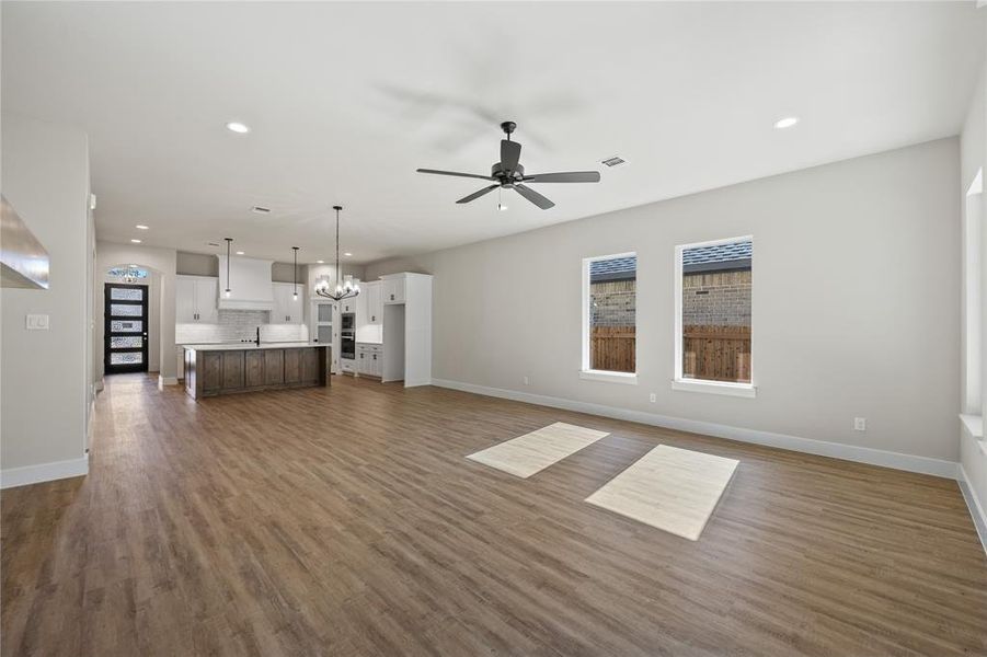 Unfurnished living room with a chandelier, dark wood-type flooring, recessed lighting, and ceiling fan