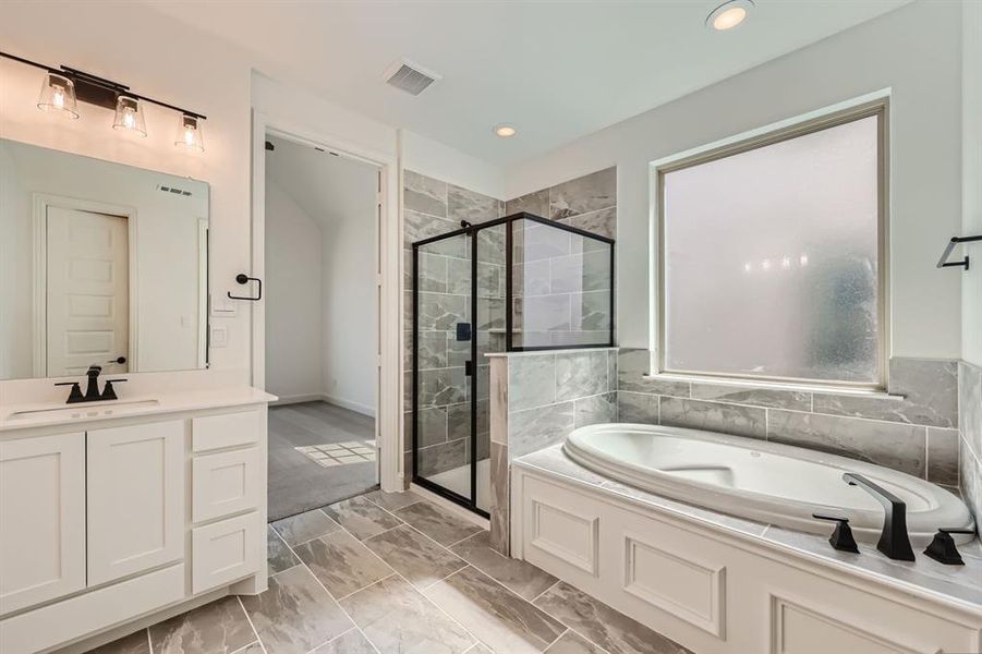 Primary bathroom featuring tile patterned flooring, independent shower and bath, and vanity