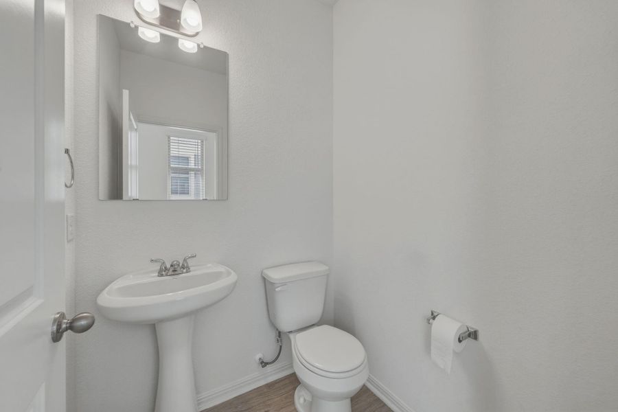 Half bath featuring toilet and light wood-style flooring
