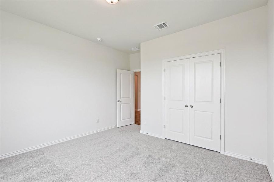 Unfurnished bedroom with light carpet and a closet