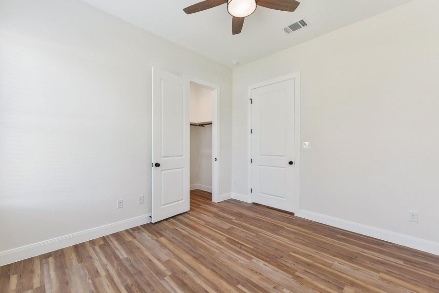 Bedroom 3 featuring visible vents, baseboards, light wood-style flooring, and a ceiling fan Bedroom 3 featuring visible vents, baseboards, light wood-style flooring, and a ceiling fan