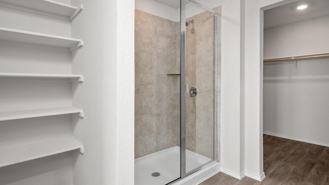 Full bath featuring a spacious closet, a shower stall, wood finished floors, and recessed lighting