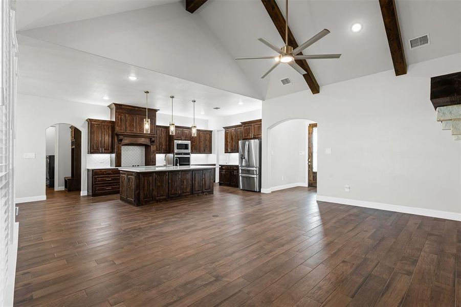 Kitchen featuring arched walkways, light countertops, dark brown cabinets, recessed lighting, and high vaulted ceiling Kitchen featuring arched walkways, light countertops, dark brown cabinets, recessed lighting, and high vaulted ceiling