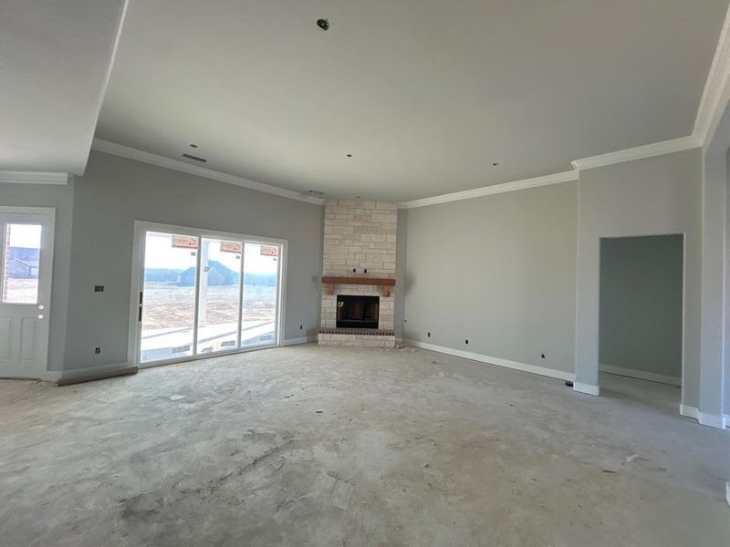 Unfurnished living room with a large fireplace, ornamental molding, and concrete floors