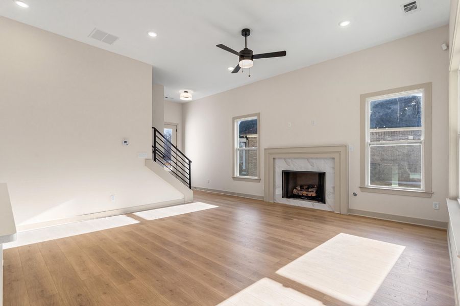 Unfurnished living room with light wood-type flooring, a ceiling fan, a premium fireplace, and recessed lighting
