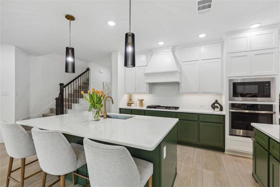 Kitchen featuring a sink, light countertops, green cabinets, stainless steel appliances, and custom range hood Kitchen featuring a sink, light countertops, green cabinets, stainless steel appliances, and custom range hood