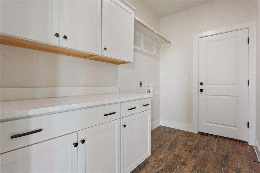 Functional laundry room offers extensive cabinetry and a convenient clothes hanging rod.