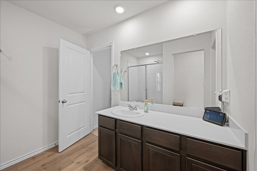 Full bath featuring a stall shower, vanity, light wood-style flooring, and recessed lighting Full bath featuring a stall shower, vanity, light wood-style flooring, and recessed lighting